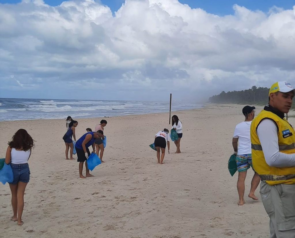 Voluntários recolhendo resíduos e lixo na areia da Praia do Francês durante o mutirão de limpeza.